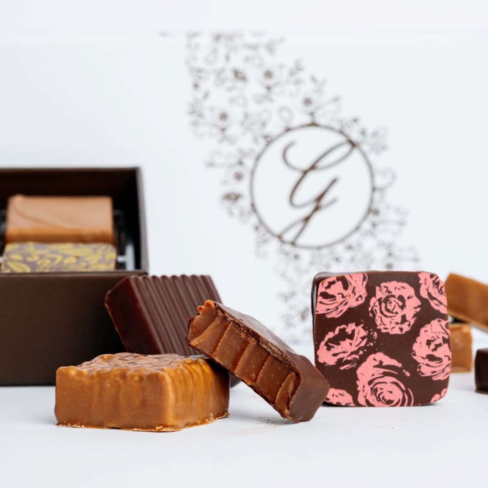 square chocolates arranged in front of chocolate boxes on white background