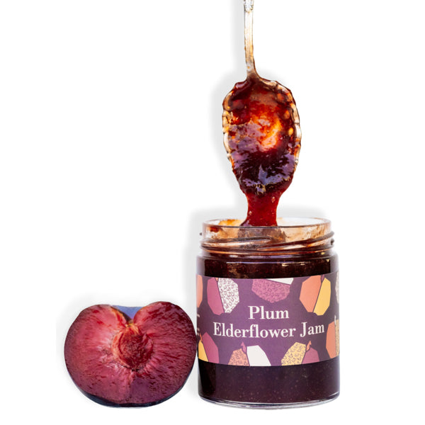 Ginger Elizabeth Chocolates Plum Elderflower Jam jar with fresh plum and dipped spoon on white background