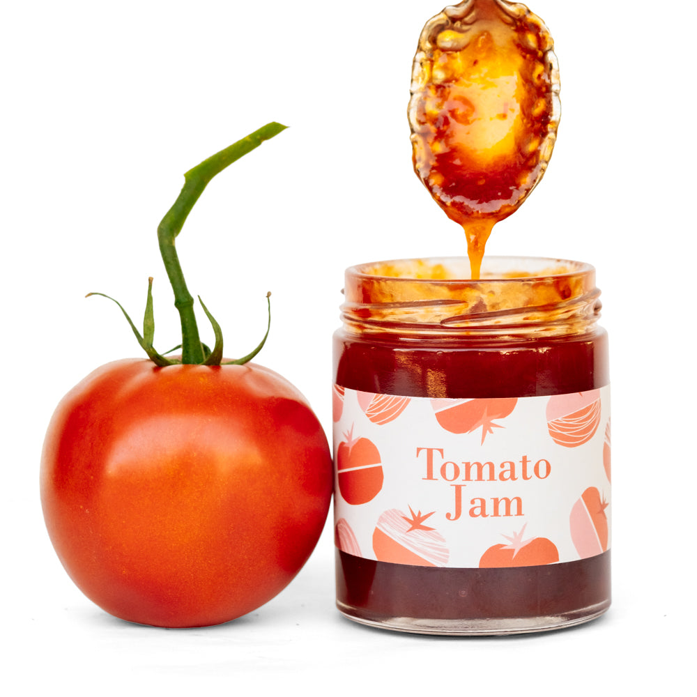 Tomato jam jar with tomato and dipped spoon on white background