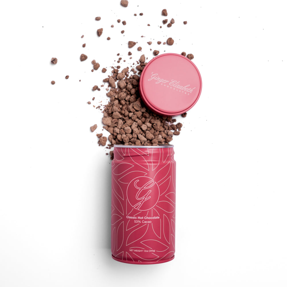 Classic Hot Chocolate Tin with lid off and above and chocolate spilling out on white background