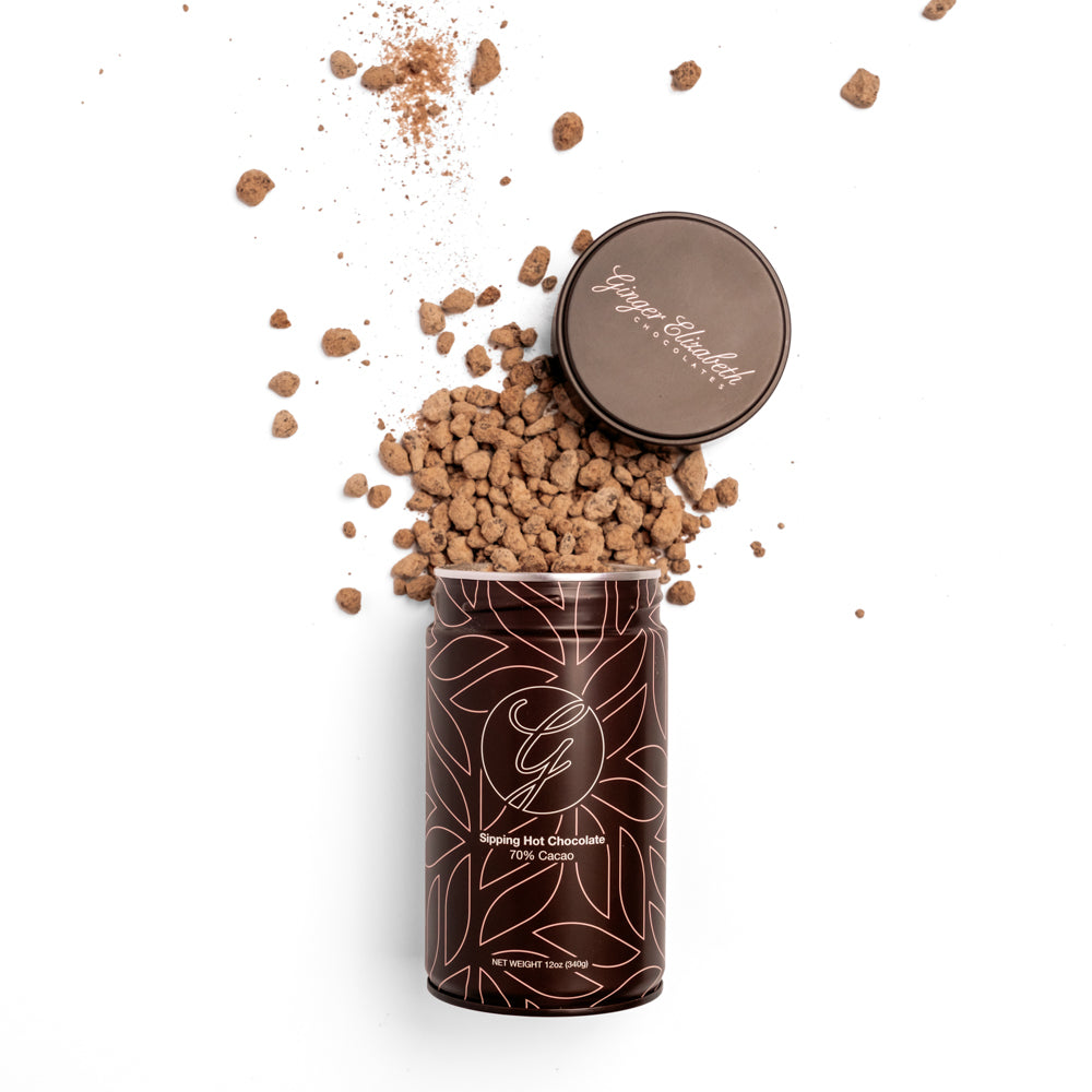 Sipping Hot Chocolate Tin open with chocolate spilling out and lid above arranged on white background