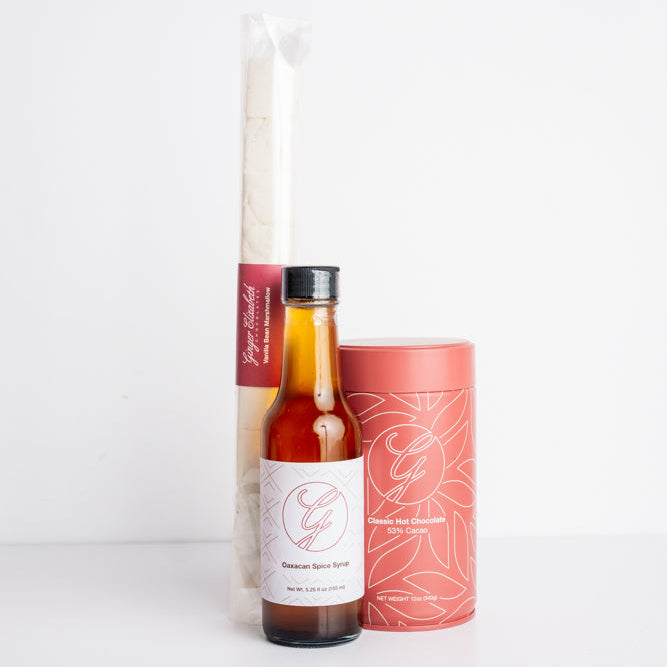 Bottle of Oaxacan syrup with a tin of hot chocolate and a package of marshmallows.