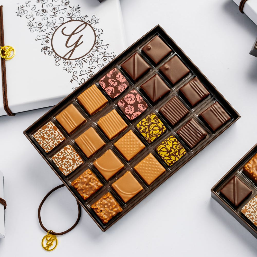 open, full 24-piece chocolate box arranged with closed boxes on white background