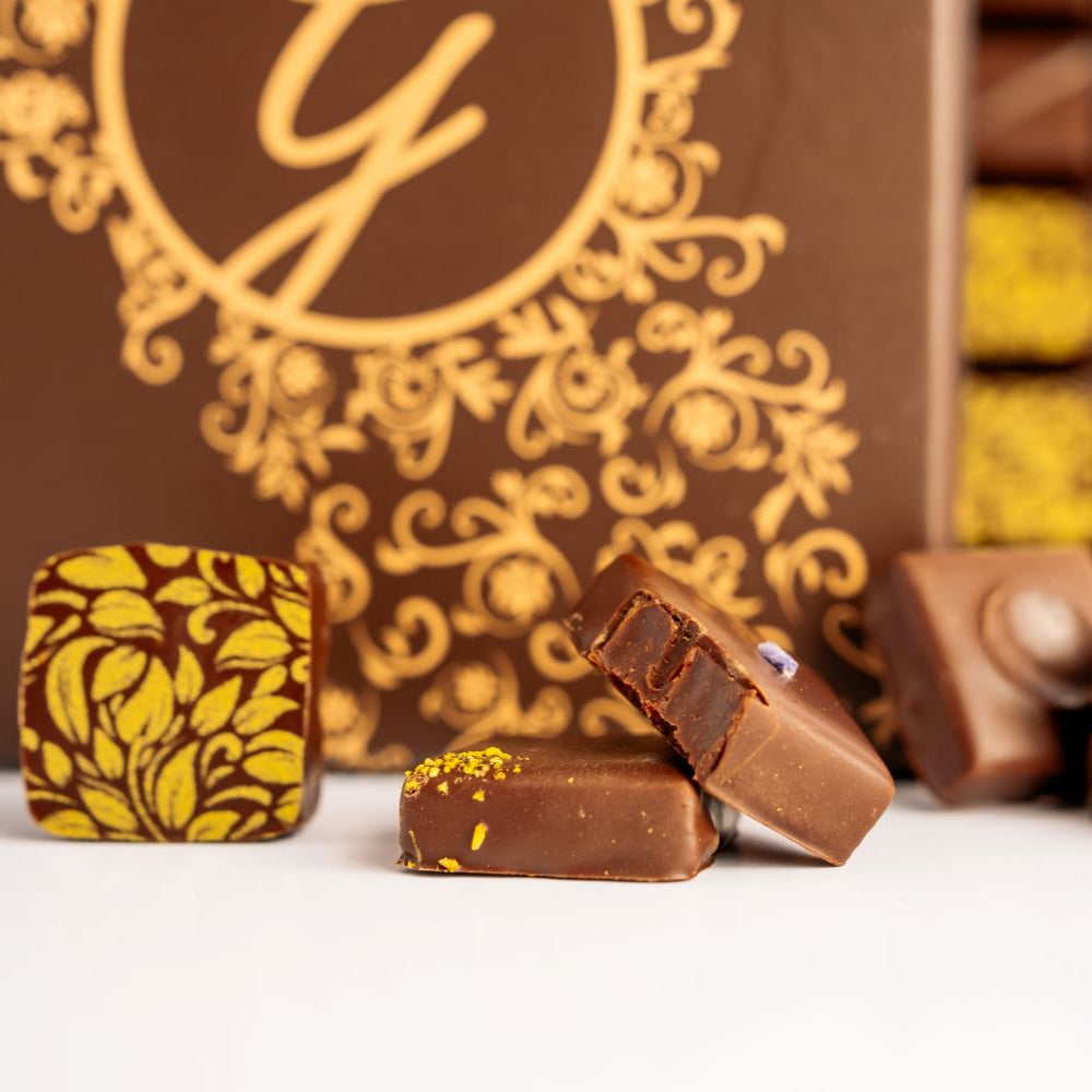 dark chocolates arranged in front of blurred open and closed boxes in background