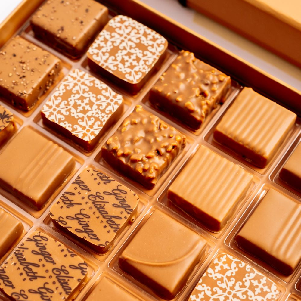 close up of open, full 24-piece milk chocolate box arranged diagonally in image on white background