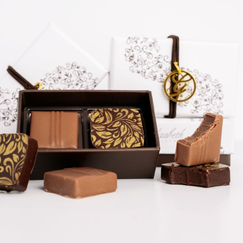 Multiple 2 piece chocolate boxes arranged with loose chocolates on a white background