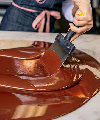Melted chocolate being spread over marble counter top. 