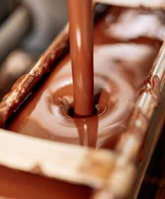 Melted chocolate being poured into chocolate mold. 