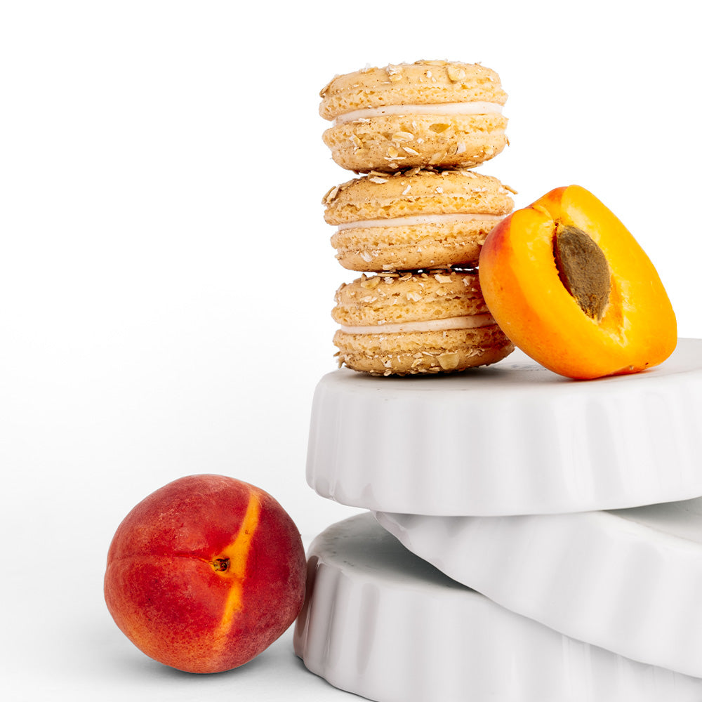 Ginger Elizabeth Chocolates stack of 3 macaron cookies balanced on white ramekin dishes with fresh fruit on white background