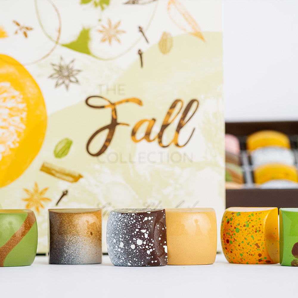 Row of fall colllection bonbons arranged in front of box with open box in background.