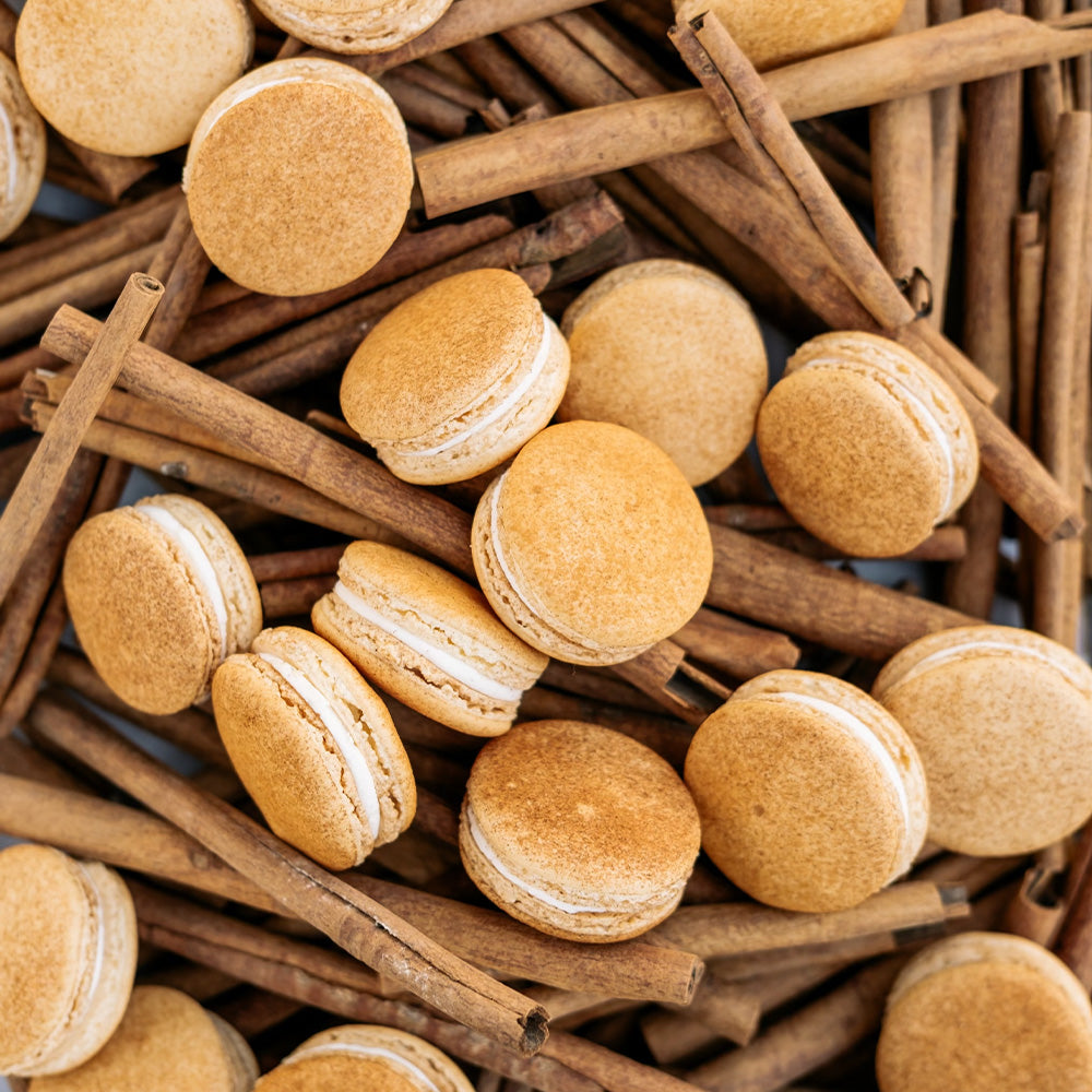 Cinnamon sprinkled macarons arranged on cinnamon sticks. 