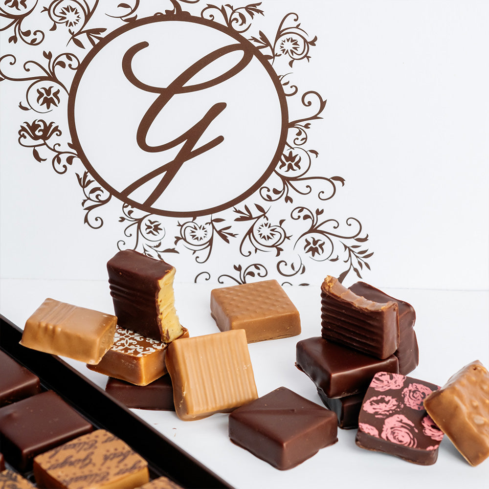 square chocolates arranged next to open and closed boxes on white background