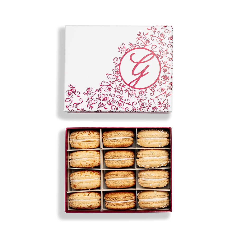 12 Piece open box of macarons and lid with pink floral G logo on white background